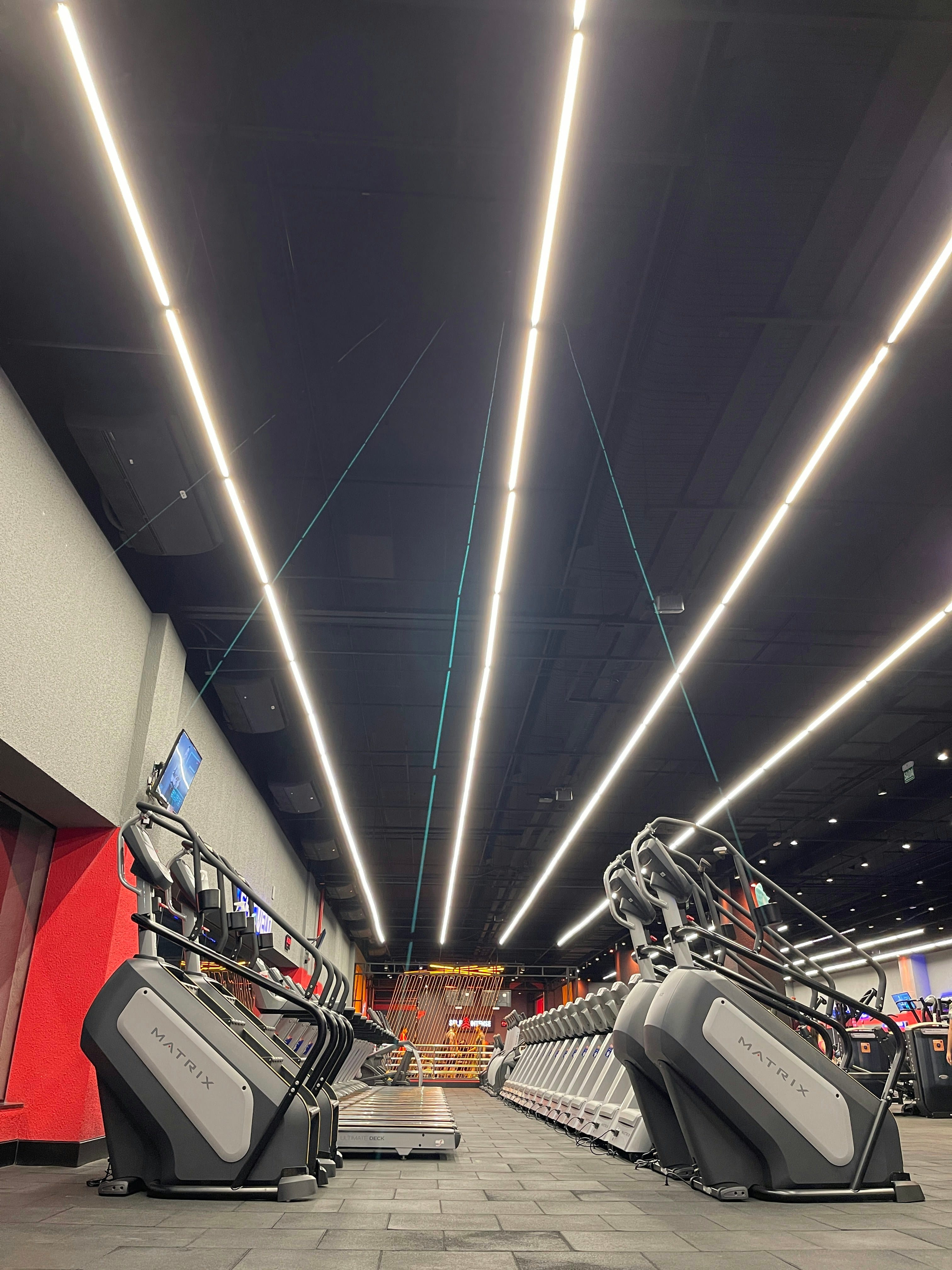 Spacious modern gym with rows of premium cardio and strength training equipment under bright LED lighting